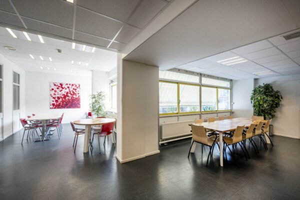 Moderne en lichte vergaderruimte aan de Jan Tooropstraat met meerdere tafels, stoelen en grote ramen met zonwering.
